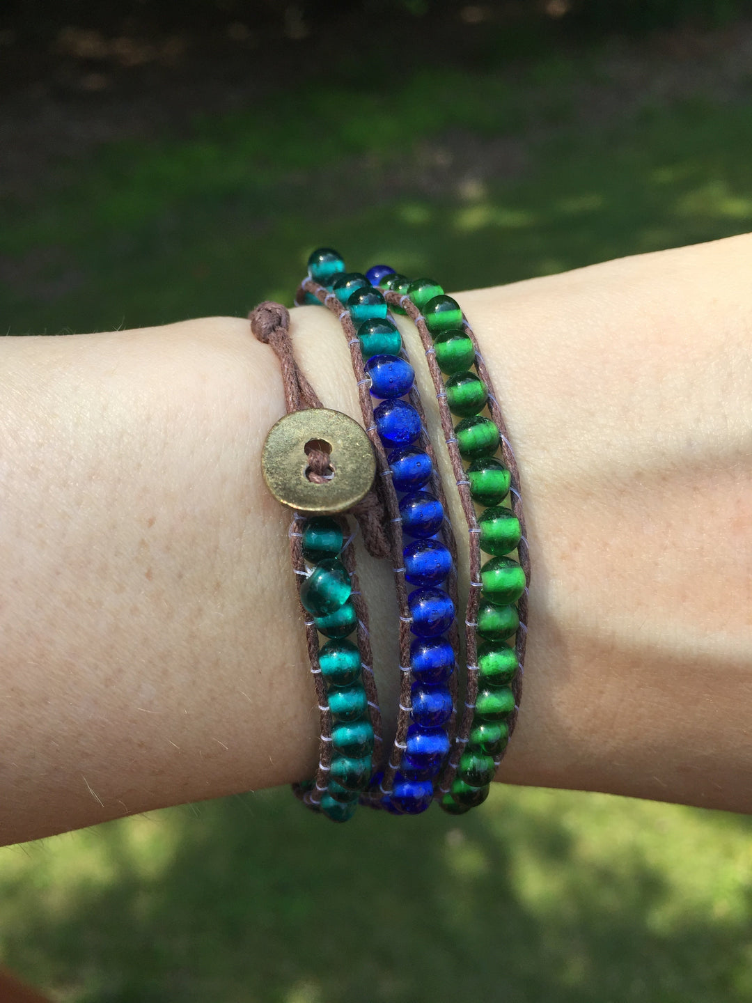 Blue, teal, green beaded wrap bracelet with brown thread and hammered copper closure